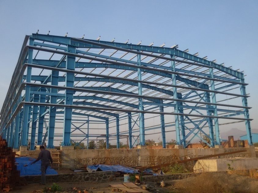 Blue structural steel frame of an industrial PEB shed at Raigad